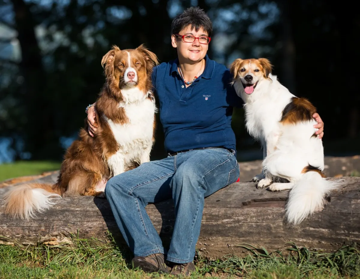 Christine sitzt mit Camillo und Fairy auf einem Baumstamm